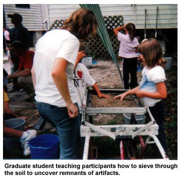 Graduate student teaching participants how to sieve through the soil to uncover remnants of artifacts. Graduate student teaching participants how to sieve through the soil to uncover remnants of artifacts.
