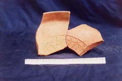 Figure 4e. Photo of a fine orange tripod dish with hematite or mica inclusions (from Matacapan, Tuxtla, Veracruz?) with an interior incised decoration showing a styled partial skull in left profile set within a series of incised lines representing a background perhaps symbolizing the sun.