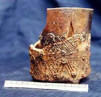Photo of the Teotihuacán-style blackware cylinder tripod with nubbin supports showing incised decoration in the form of triangular elements with zones of punctate and tiny skull-like appliques.